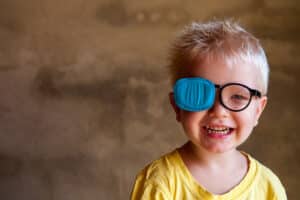 Smiling boy with a patch over one eye for lazy eye treatment in UT